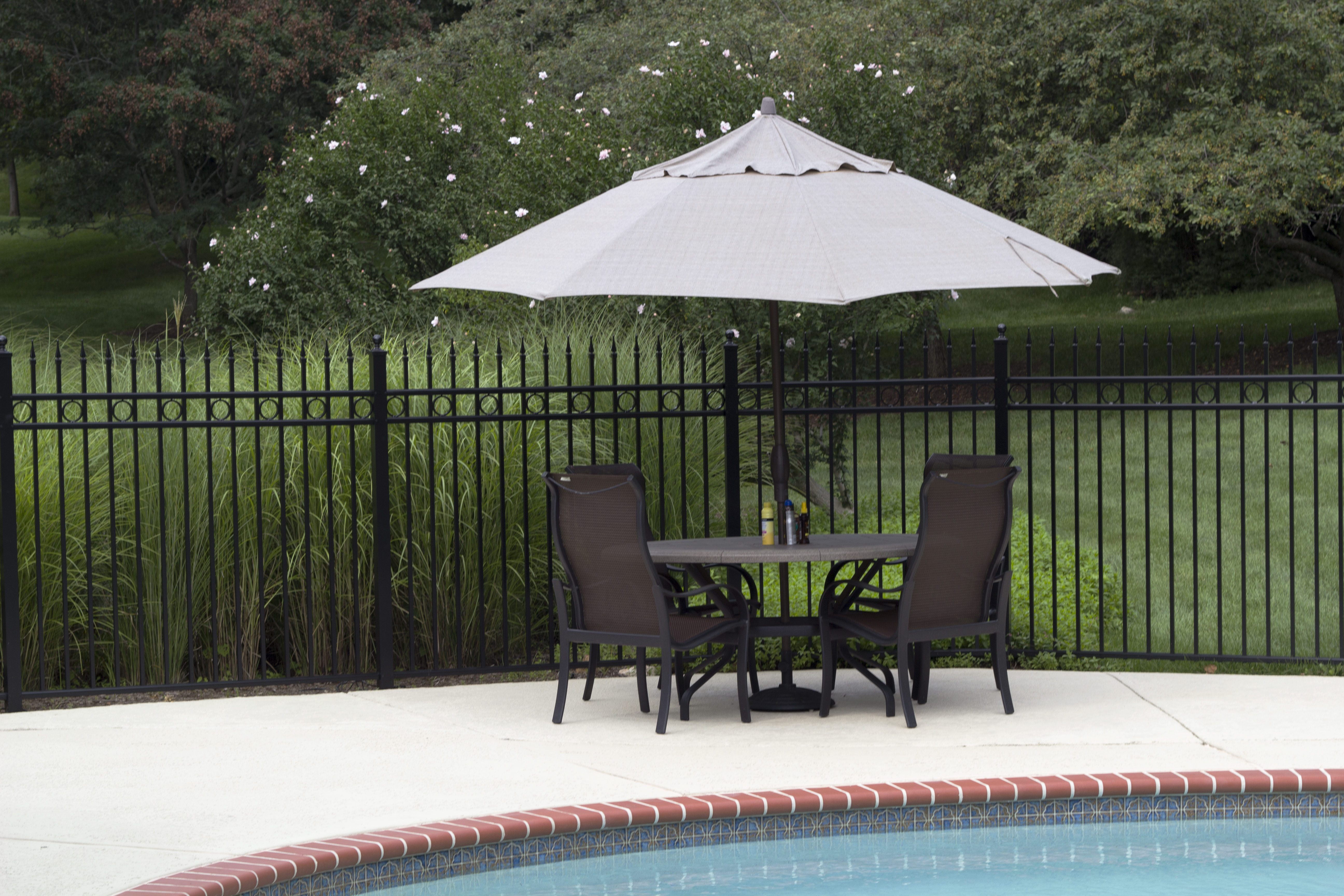 metal fence near table and chairs and pools