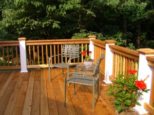 Two chairs and flowerpots on gorgeous wood deck with rails 