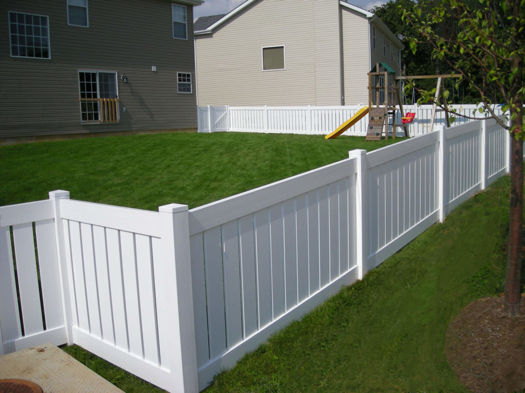 a Prestige vinyl fence enclosing a backyard with a playground