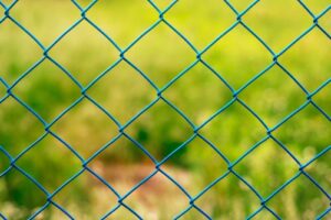 close-up of chain link fence with grassy background