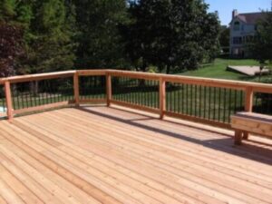 Sunny view of newly built wooden deck overlooking lawn and trees
