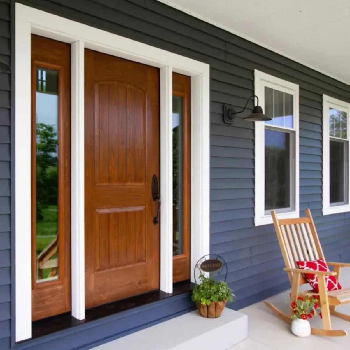 Beautiful solid wood front door with side windows on a blue house