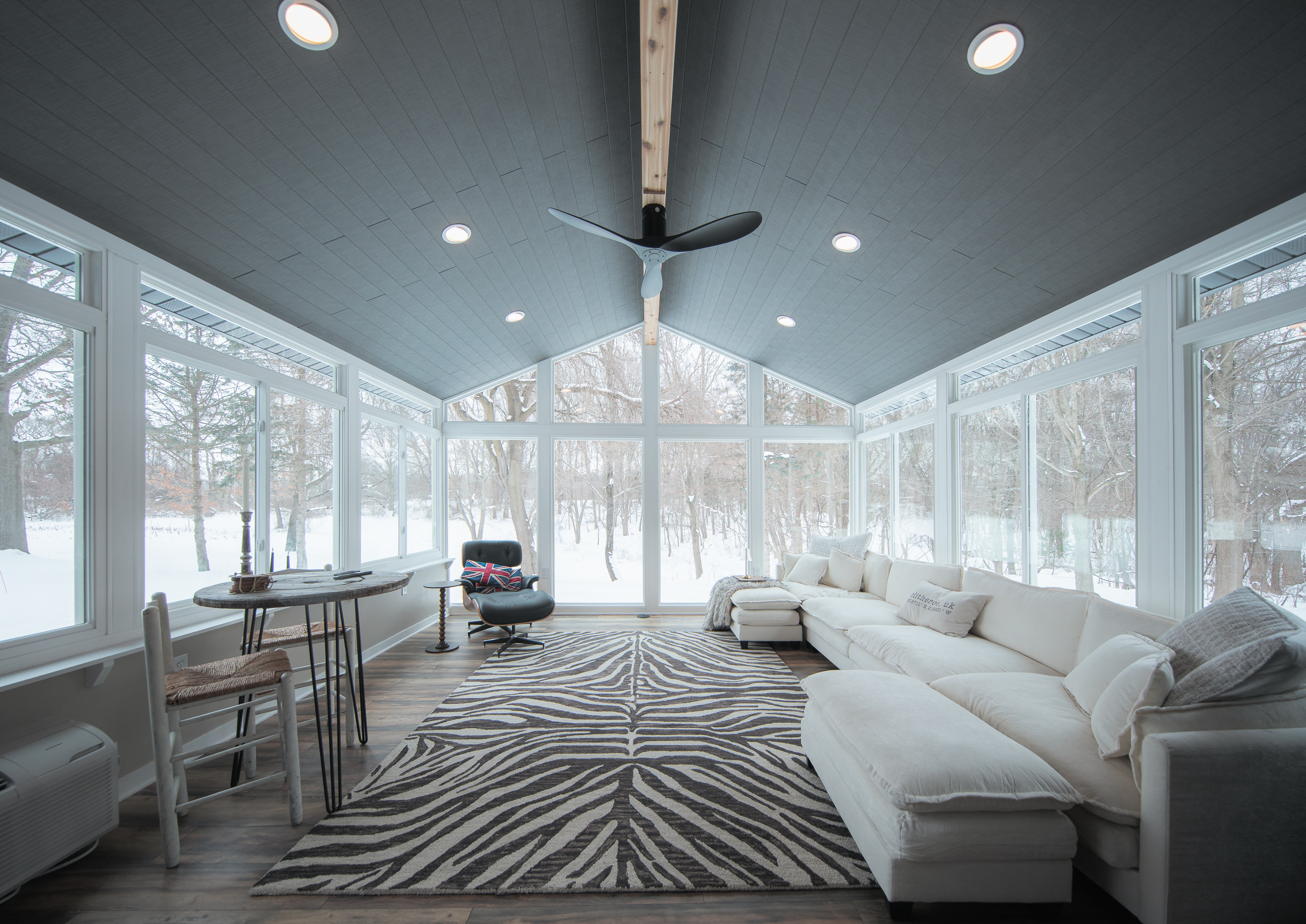 Modern sunroom with large windows and comfortable seating while outlooking snow
