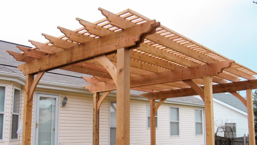 Double wood pergola in backyard of off white ranch house