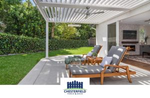 White louvered pergola above an outdoor patio with a ceiling fan
