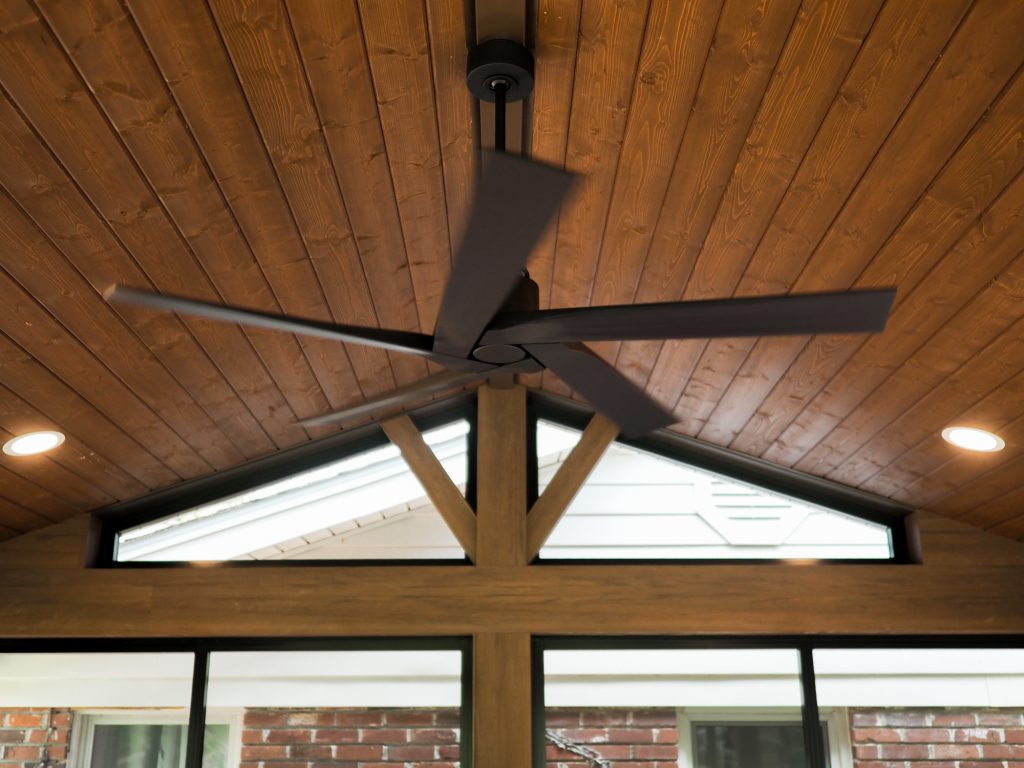 Screen room fan with a wood panel roof interior and lights